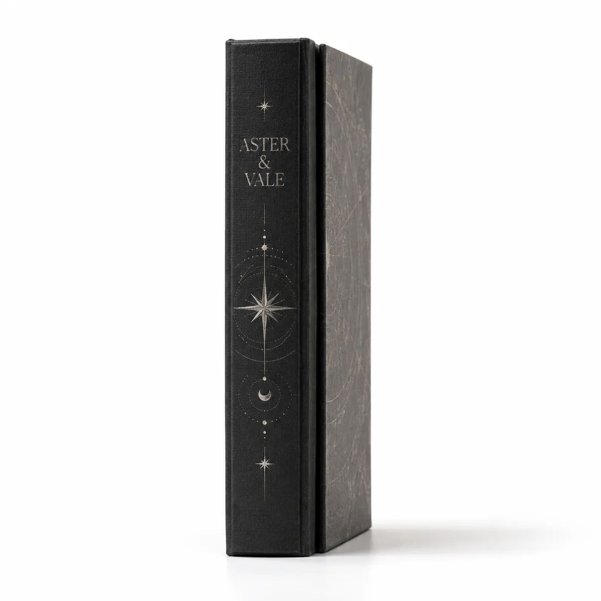 Side-profile view of a charcoal Aster & Vale rigid fragrance box with silver celestial illustrations and a hardcover-style spine.