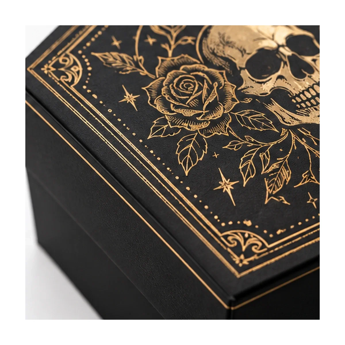 Close-up of a coffin gift box lid showing gold-colored skull and rose linework, ornate border and black textured surface.