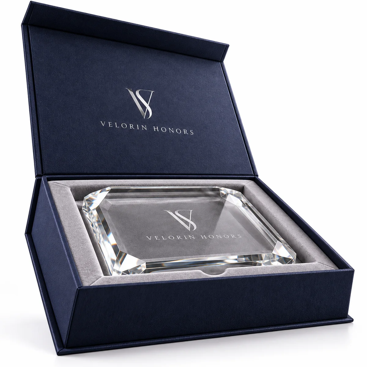 Angled front view of a navy rigid award presentation box with a raised branded lid and crystal plaque in a velvet-lined tray.