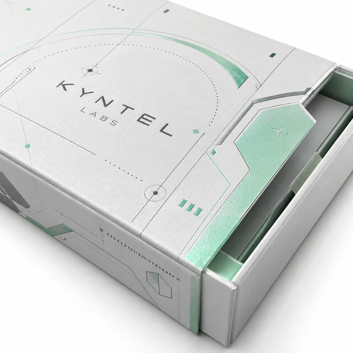 Close-up of a pearl white Kyntel Labs booklet box showing mint geometric printing, a folded closure flap, and part of the inner tray.
