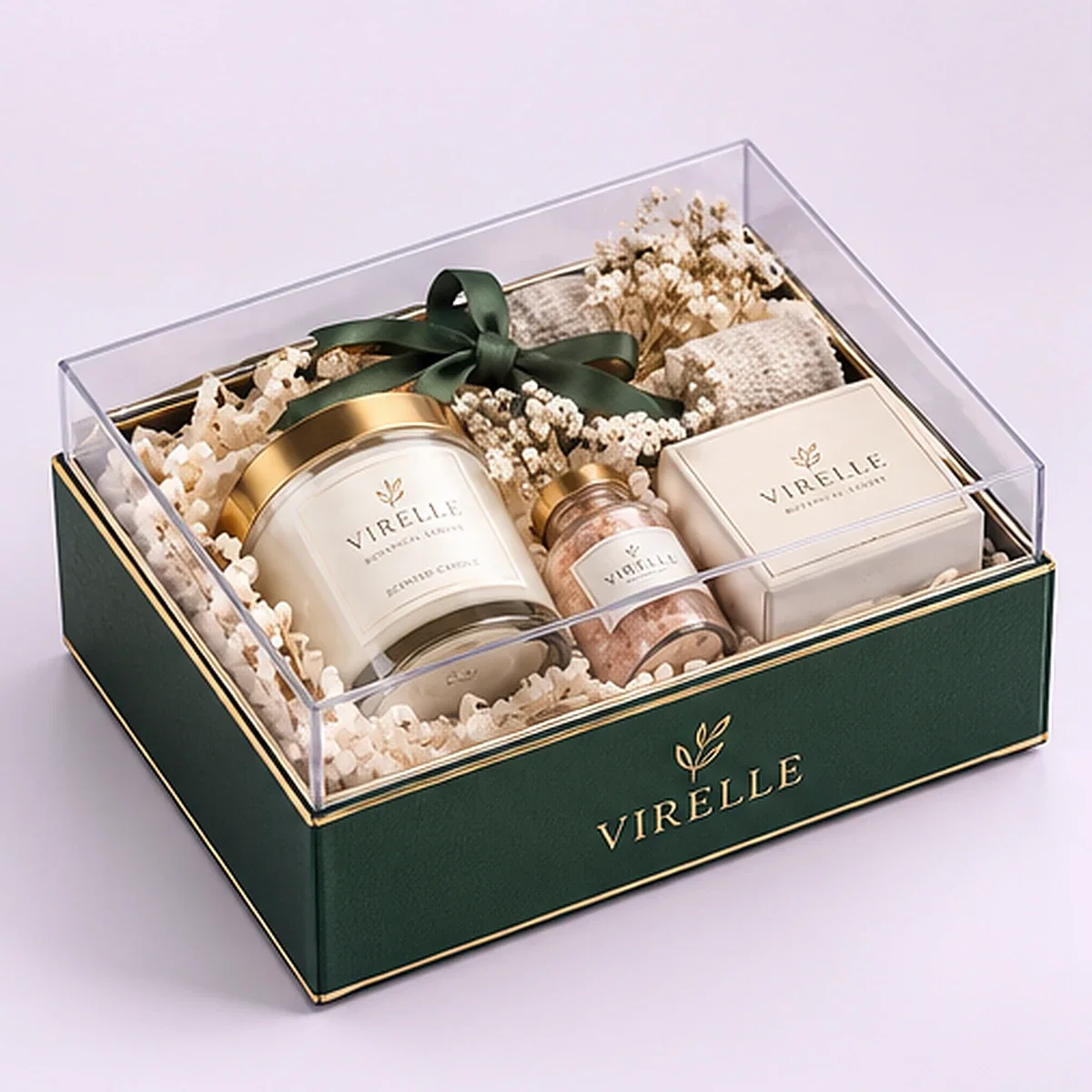 Angled view of VIRELLE custom clear lid gift box with dark green branded tray, candle, bath salts, soap, ribbon and filler.