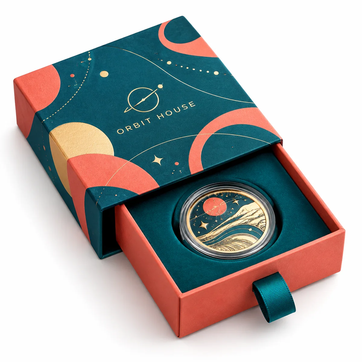 Teal and coral rigid drawer coin box with celestial artwork, ribbon pull, and a collectible coin in a fitted insert.