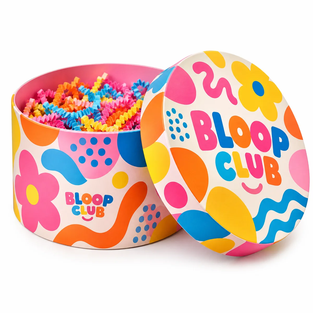 Open BLOOP CLUB round gift box with pink, orange, blue and yellow graphics and multicolored shredded paper inside.