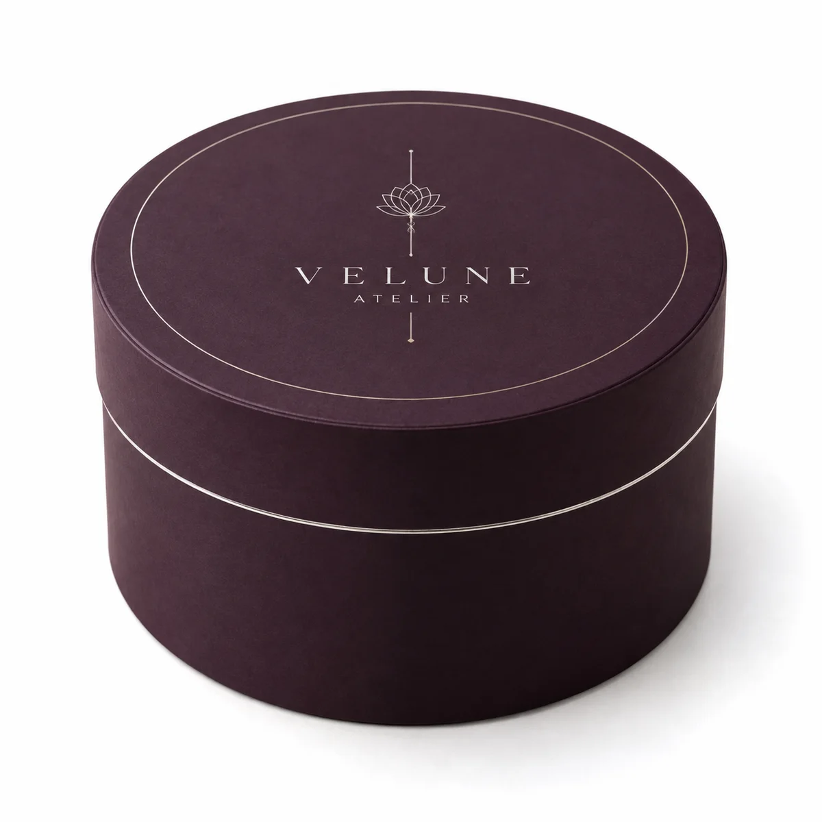 Deep aubergine round gift box with fitted lid, thin metallic borders and elegant VELUNE ATELIER branding.