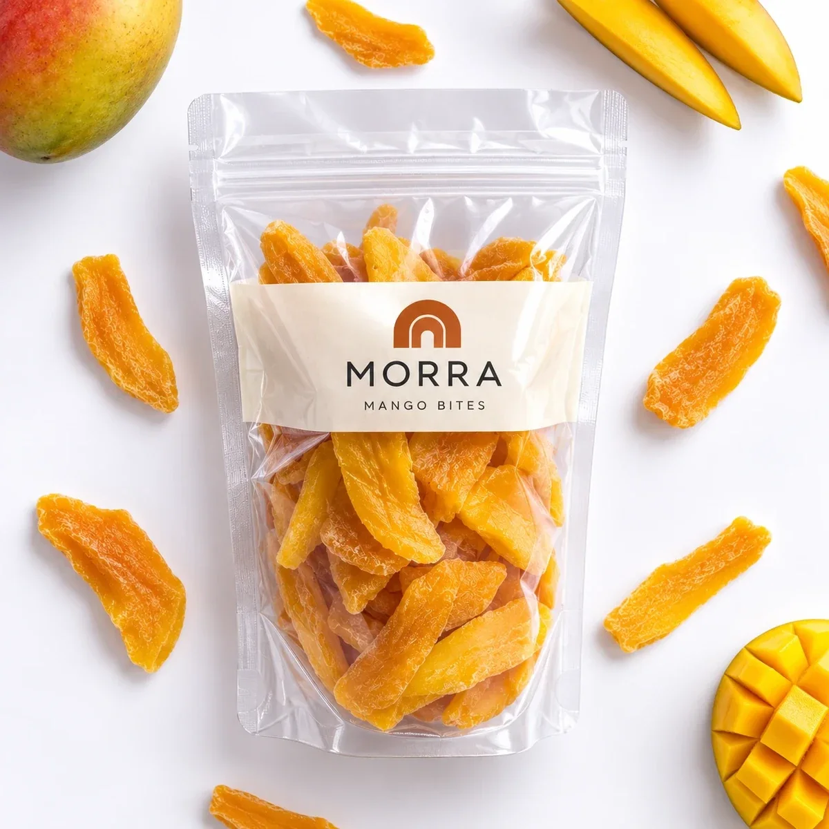 Flat-lay photo of a transparent MORRA Mango Bites zipper pouch surrounded by dried mango pieces on white.