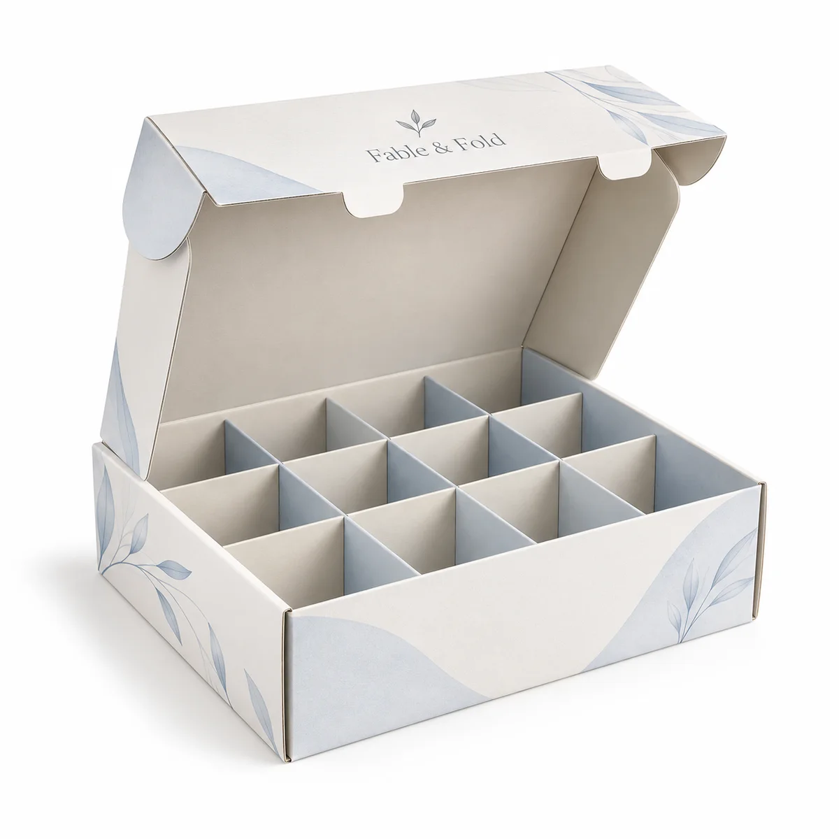 Open Fable & Fold cardboard box with twelve dividers, ivory panels, pale blue botanical details, and a hinged lid.