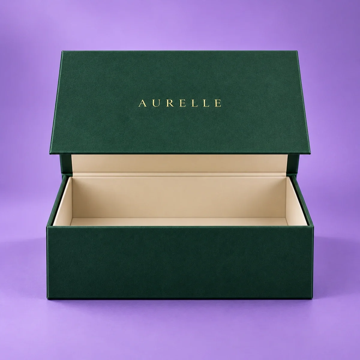 Straight-on front view of an open magnetic gift box with a dark green exterior, gold AURELLE branding, and ivory lining