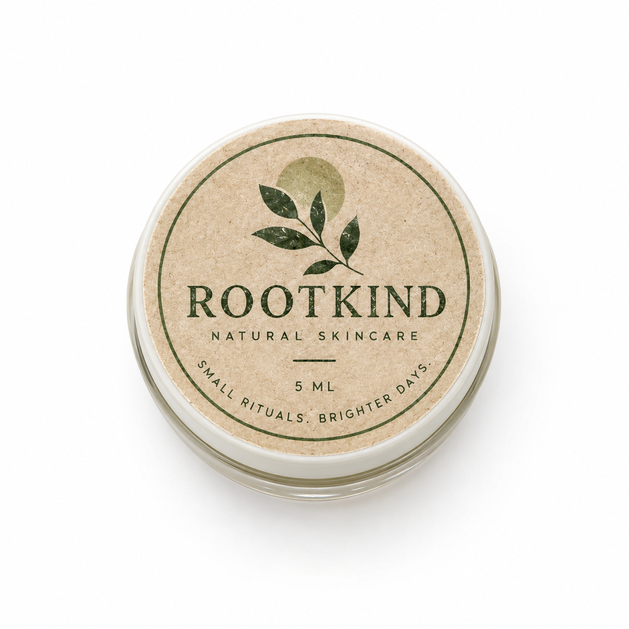 Top-down 5ml cosmetic jar with kraft-style lid label, forest green botanical mark, and ROOTKIND branding.
