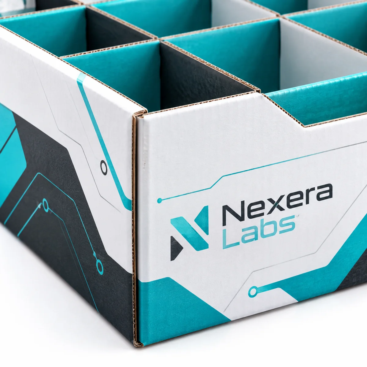 Close-up of a Nexera Labs cardboard divider box showing teal and black partition walls, geometric artwork, and exposed board edges.